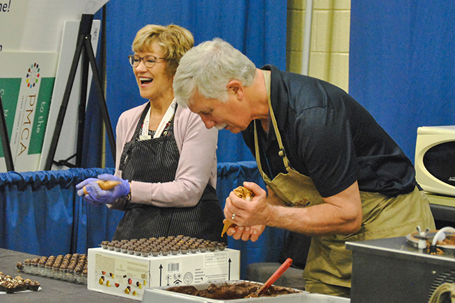 two volunteers making candy in booth