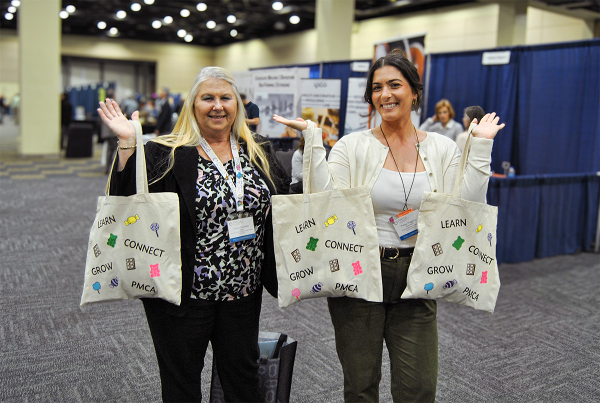 two smiling attendees with tote bags